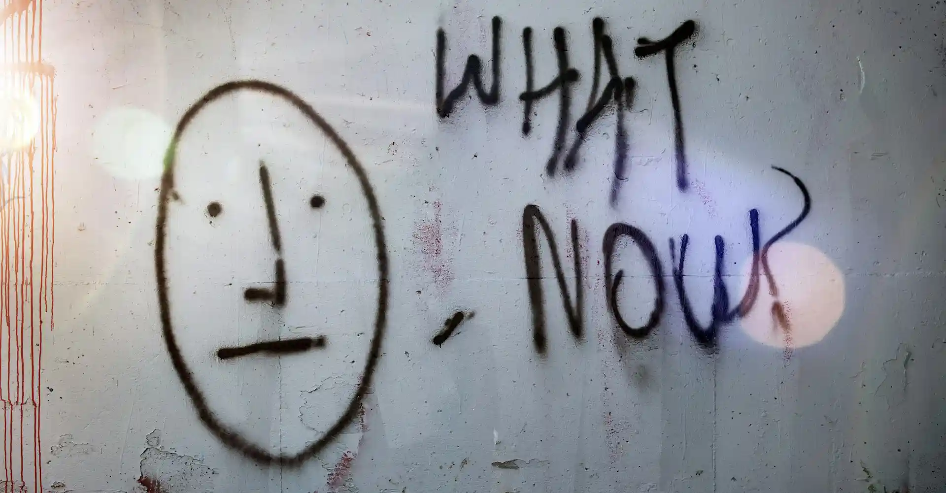 Gnervtes Smiley an einer Wand "what now?"-Tagging
